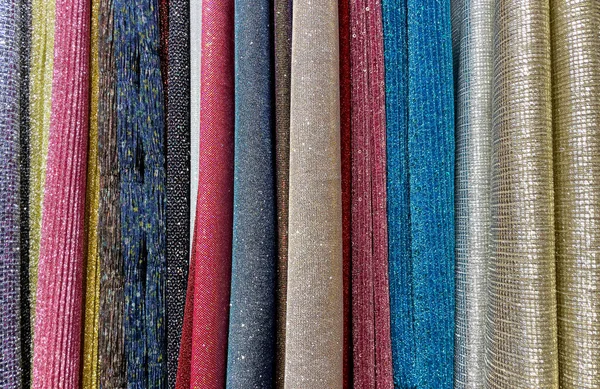 multi-colored curtains in the store. texture of multi-colored fabrics, close up. samples of multi-colored fabric close-up. multi-colored fabric hanging in a store. Fabric colour and texture swatches.