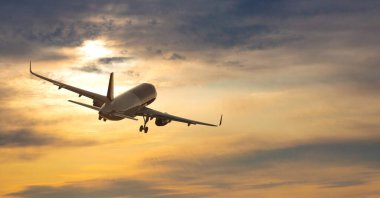 Uçak. Renkli günbatımında sarı gökyüzünde büyük beyaz yolcu uçağıyla manzara uçuyor. Yolculuk. Yolcu uçağı alacakaranlıkta inecek. İş gezisi. Ticari uçak.