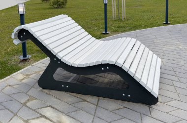 Şehir parkının kaldırımlı yollarının kenarında duran modern ahşap bank