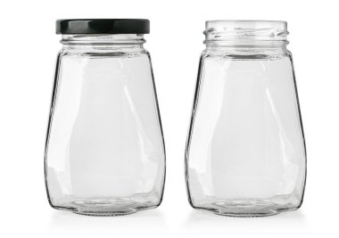 Beyaz arka planda izole edilmiş iki boş cam kavanoz. Birinin kapağı siyah, diğerinin açık.