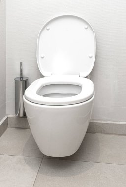 Modern bir tuvalette kapağı açık, tuvalet fırçası da açık.