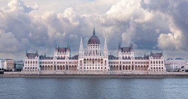 Dramatik bulutlar altındaki süslü Macar parlamento binası Danube Nehri 'ne yansıyor