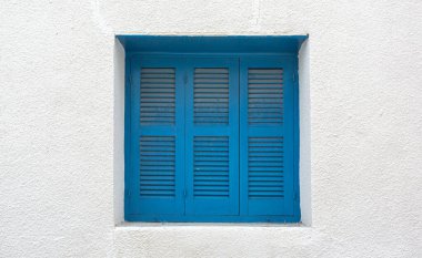 Geleneksel mavi pencere panjurları, basit beyaz duvara renk katarak, Akdeniz atmosferi yaratıyor.