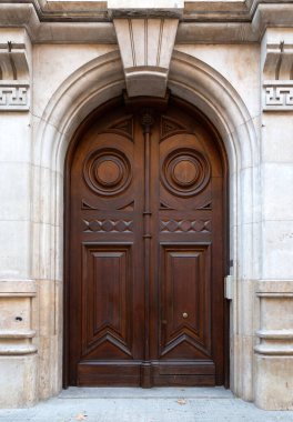 Klasik ahşap kapılar. Karmaşık oymalar var. Kemerli bir taş kemer içinde geçiyor.