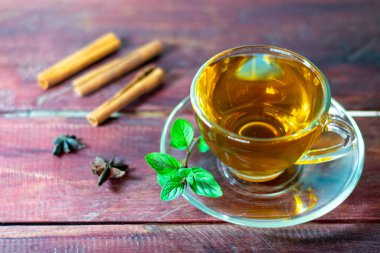 Nane çayı ahşap masada taze nane yaprakları ve tarçınla.