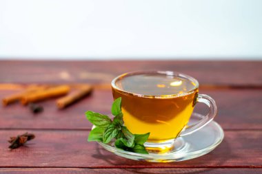 Nane çayı ahşap masada taze nane yaprakları ve tarçınla.