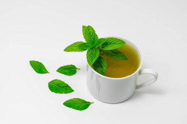 Beyaz arka planda izole edilmiş beyaz bardakta nane çayı..