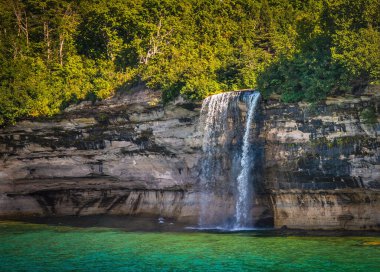 Tall Bridalveil waterfall flows over Lake shore cliff