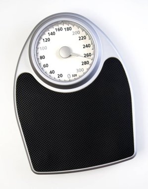 A traditional analog weight scale with a black surface and a white dial. clipart