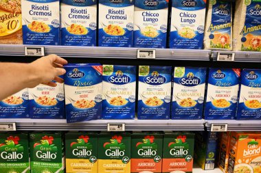 BARI, İtalya HAZİRAN 2023: Carrefour süpermarketindeki karton ambalajlarda farklı pirinç ürünleri çeşitlerinden seçilen müşteri.