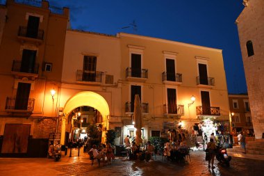 BARI, İtalya - Temmuz 2023: Alacakaranlıkta eski Bari kentindeki Piazza dell Odegitria 'da bir kaldırım kafesinde turistler 