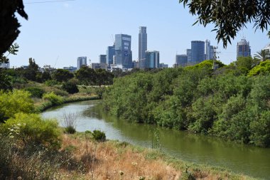 TEL AVIV-YAFO, ISRAEL - MAYIS 2023: Yarkon nehri Ramat Gan Elmas Borsası Bölgesi 'nin arka planındaki şehir parkından akıyor