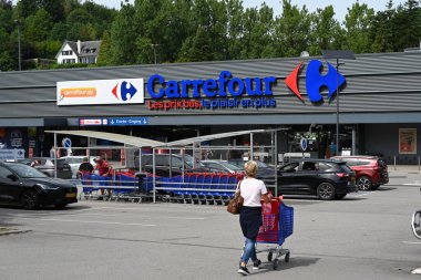 MALMEDY, BELGIUM - AĞUSTOS 2023: alışveriş arabalı bir kadın Carrefour hipermarketinde alışverişe gider. Ticari isim altında metin sloganı: düşük fiyatlar, daha eğlenceli