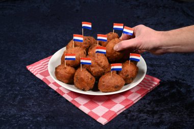 El, Hollanda bayraklı bir kase oliebollen 'den bir çörek alır. Hollanda 'da yeni yıl arifesi için geleneksel gıda.