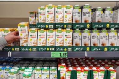 GERMANY - HAZİRAN 2024: Müşteri, Lidl süpermarketindeki çeşitli süt ürünlerinden biyomarka yulaf sütü seçti
