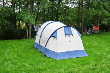 Belçika Ardennes 'deki kamp alanının çimlerinin yanındaki derenin yanındaki pamuk tünel çadırı.