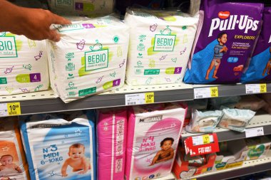 AVUSTOS 2023: Alışveriştekiler, Delhaize 'deki bir süpermarkette farklı marka bebek bezlerinden BEBIO marka tek kullanımlık bebek bezi seçiyor.