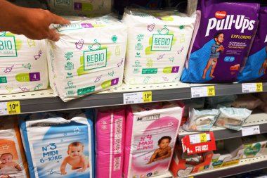 BELGIUM - AUGUST 2023: Shopper select BEBIO brand eco disposable diapers of shelves various brands diapers in a Delhaize supermarket clipart