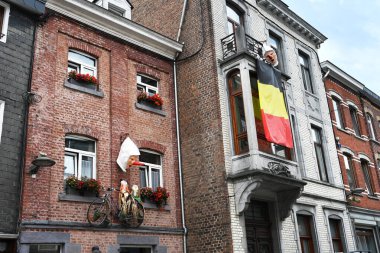 BELGIUM - AUGUST 2023: Facade with decoration of a Belgian flag and Masker with long red noses, the Blancs-Moussis, a traditional carnival attribute in town of Stavelot clipart