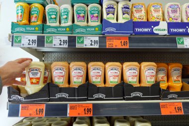 ALMANY - Nisan 2024: Alışverişçi bir süpermarkette sıkılmış Heinz marka sos şişesi seçer. Heinz, Kraft Heinz Şirketi 'ne ait bir marka.