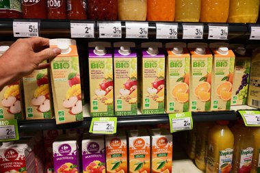 WALLONIA, BELGIUM - MAYIS 2025: Müşteri Carrefour 'un özel markasını seçer, Biyoloji etiketi meyve sularını bir süpermarkette sergilenen meyve sularından tütsüler..