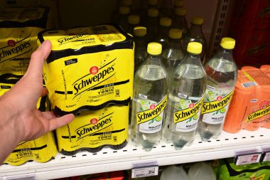 WALLONIA, BELGIUM - AĞUSTOS 2024: Alışverişçi, Carrefour süpermarketindeki Schweppes marka soda içeceklerden altı paket tonik seçti