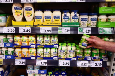 Müşteri, Kaufland süpermarketinde mayonez ve çeşitli markaların soslarıyla dolu raflardan bir kavanoz remoulade sosu seçiyor. Thomy, Nestl 'e ait bir İsviçre gıda markası..