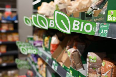 ALMANY - AĞUSTOS 2025: Kaufland hipermarketindeki organik gıda haznelerinin raflarına BIO etiketleri yapıştırmak