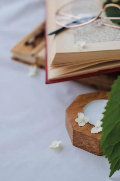 stock image Open book with hydrangea flowers and glasses on white bed