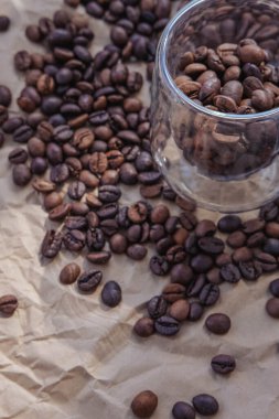Cam kavanozdaki kahve çekirdekleri buruşmuş kağıt arka planda.