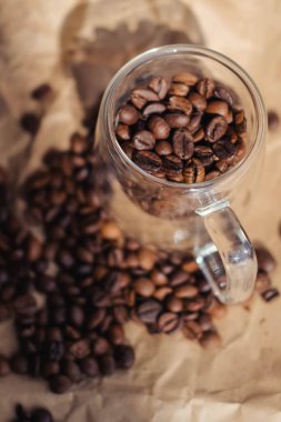 Cam kavanozdaki kahve çekirdekleri buruşmuş kağıt arka planda.