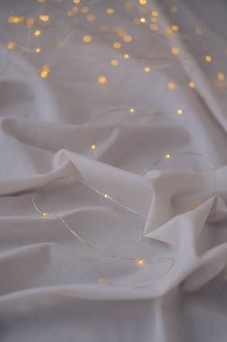 Beyaz kumaş arka planda Noel ışıkları. Noel ve Yeni Yıl kavramı.