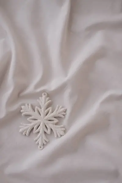 Beyaz kumaş üzerinde beyaz kar tanesi. Noel ve Yeni Yıl kavramı.