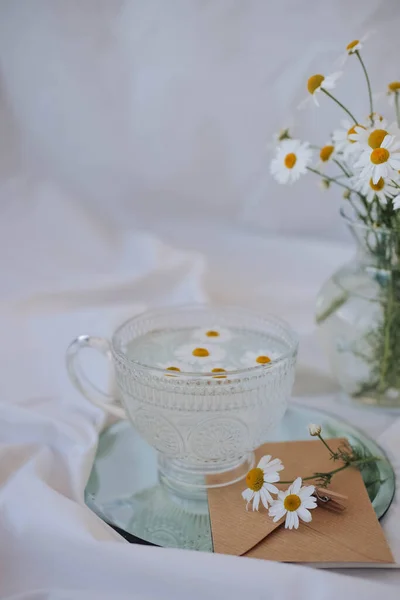 Beyaz arka planda papatya çiçekleri olan bir fincan çay.