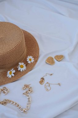 Papatya çiçekli hasır şapka ve yatağın üzerinde kitaplar