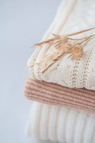 Beyaz arka planda kurumuş çiçekli sıcak örülü süveter yığını.