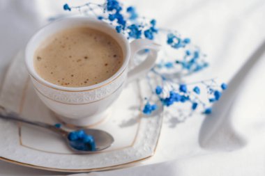 Sütlü kahve ve beyaz arka planda mavi çigila çiçekleri.