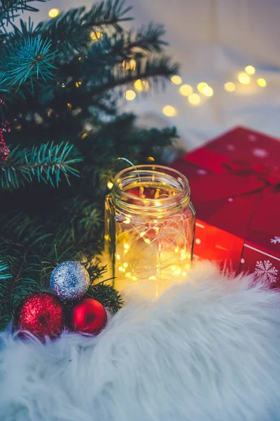 Beyaz kumaş arka planında kırmızı hediye kutusu olan Noel ağacı