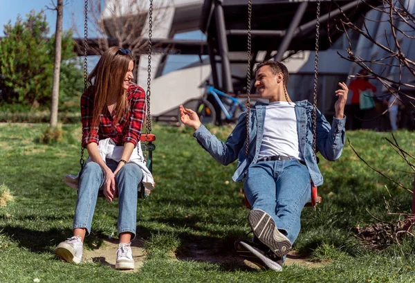 かわいいカップルがキャロルの上に座って公園で話している — ストック写真