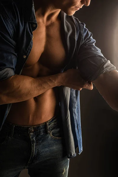 Attractive and handsome guy is posing and fixing his sleeve in studio, close up