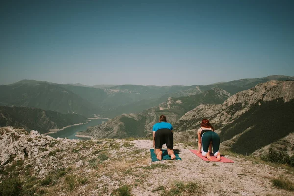 ヨガのカップルは山の上でヨガをしています — ストック写真