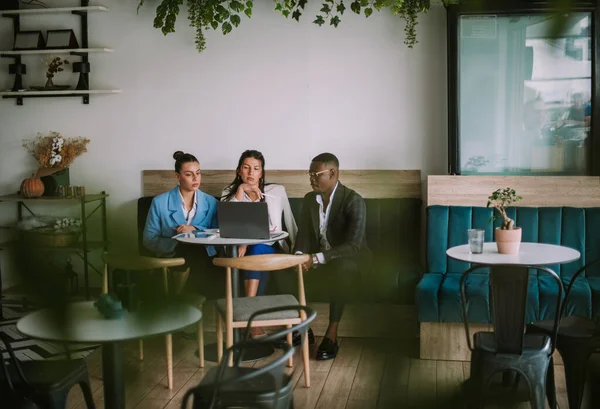 Drie Zakenmensen Kijken Naar Laptop Terwijl Blauwe Bank Het Café — Stockfoto