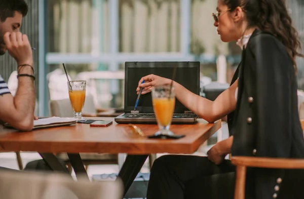 Bizneswoman Wskazując Prezentację Laptopie Podczas Siedzenia Swoim Partnerem Kawiarni — Zdjęcie stockowe