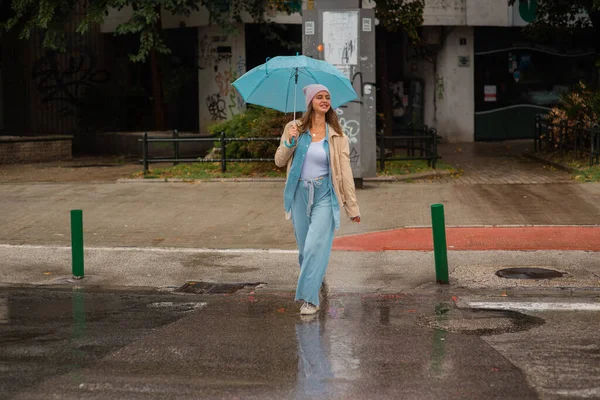 Chica Atractiva Sonríe Mientras Cruza Calle Bajo Lluvia Con Paraguas — Foto de Stock