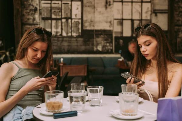 Zwei Hübsche Mädchen Die Café Auf Ihren Telefonen Sms Schreiben — Stockfoto