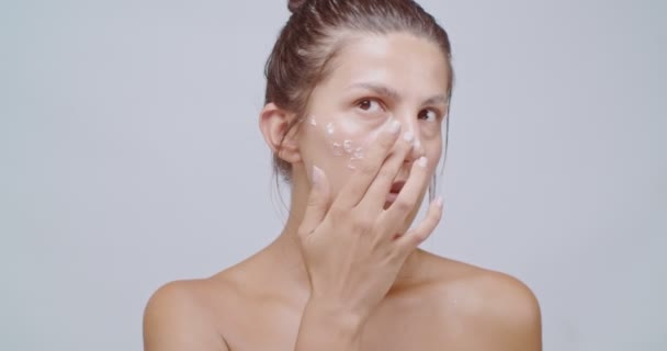 漂亮的女人在脸上涂上白霜 按摩它 洁肤洁肤 面容清澈 护肤治疗或化妆品广告概念 — 图库视频影像