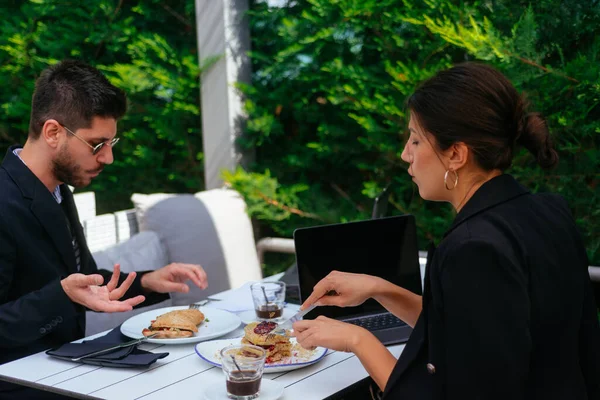 素敵なビジネスマンの女性は彼女の朝食を食べている 彼女のハンサムなパートナーはそれの味が好きではありません — ストック写真