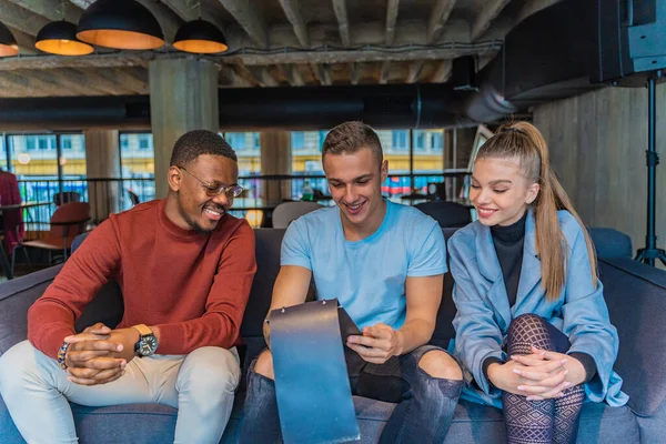 stock image Three multiracial friends are looking at the menu together while smiling