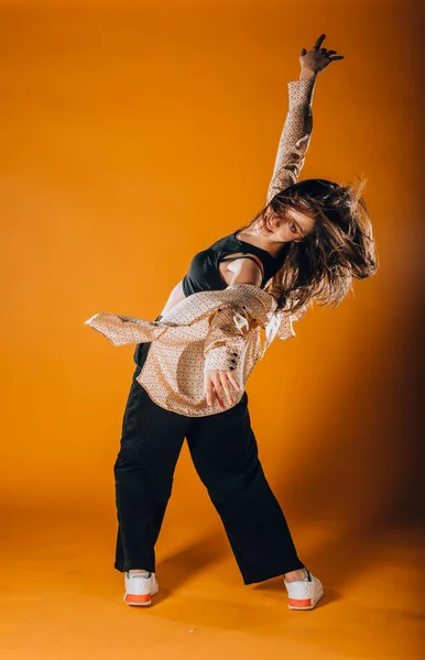 在橙色墙上跳当代舞蹈的白人女舞蹈家 — 图库照片