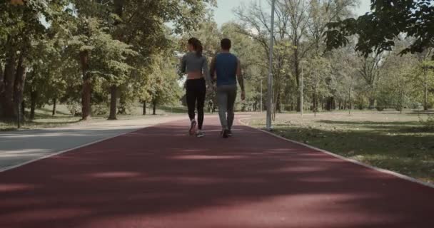 公園のランニングコースを歩いているカップルは 走り出す準備ができています — ストック動画